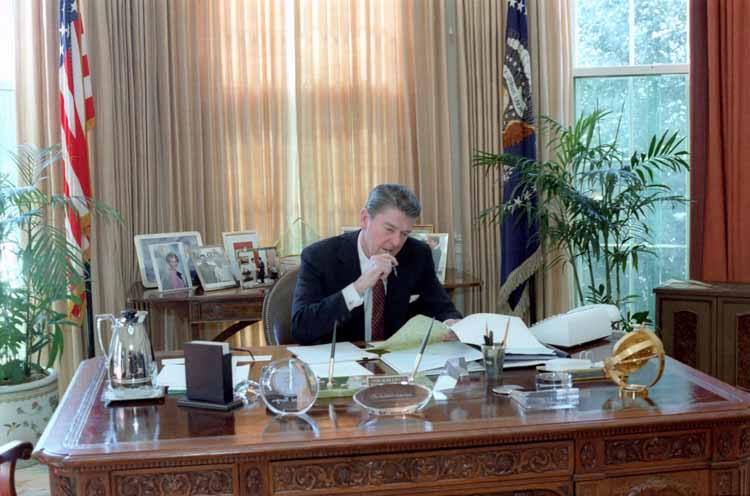 President Ronald Reagan working at his desk in the Oval Office.