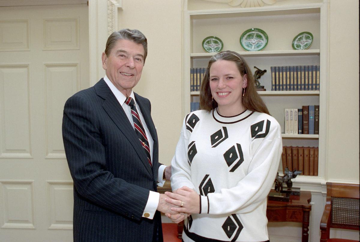 President Reagan shaking hands with Sue Daoulas, 12/19/1988, c51122-9