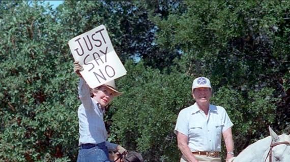 Nancy Reagan holds up a “Just Say No” sign for distant press photographs while riding with President Ronald Reagan at Rancho del Cielo, California C36731-26 dated 09/06/1986 NAID: 75855005