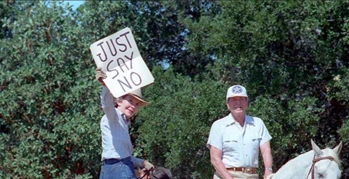 Nancy Reagan holds up a “Just Say No” sign for distant press photographs while riding with President Ronald Reagan at Rancho del Cielo, California C36731-26 dated 09/06/1986 NAID: 75855005