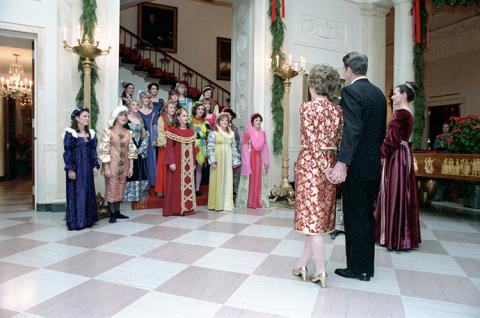 C19118-7, President Reagan and Nancy Reagan listening to an unidentified choir performing at the White House during Christmas party for members of the United States Secret Service and their families. 12/19/1983.