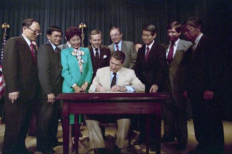 President Ronald Reagan Signs The Reparations Bill for Japanese-Americans with Pete Wilson, Spark Matsunaga, Norman Mineta, Robert Masui, and Bill Lowrey Looking on in The Old Executive Office Building