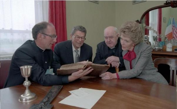 President Ronald Reagan, Nancy Reagan, Father Eanna Condon, and Father Murphy look through baptismal records at Church of the Assumption in Ballyporeen, Ireland 
