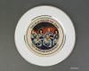 Commemorative Plate – Challenger Artifact ID: 1986.90766.01 Object Name: Plate, Commemorative Maker: Star Glaze Inc., Hialeah, Florida Date Made: 1986. Description: A commemorative white ceramic plate with a gold edge detailing. At the center of the plate is an image of the seven astronauts from the Challenger space shuttle, with the text "THE REACHED FOR THE STARS THEY ACHIEVED IMMORTALITY."