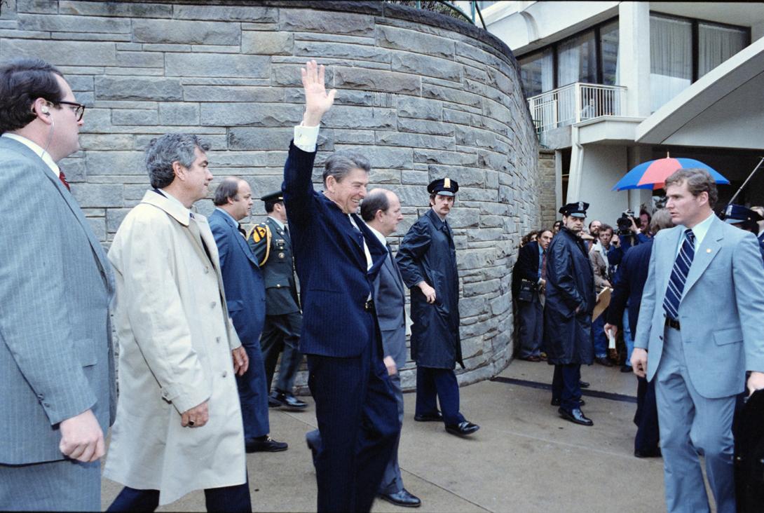 President Ronald Reagan waves to the crowd immediately before being shot in an assassination attempt after exiting the Washington Hilton Hotel 03/30/1981  NAID: 75852767