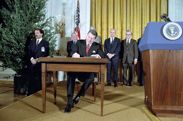President Ronald Reagan signing Proclamations 5003 and 5004 to Commemorate Human Rights Week and the First Anniversary of Martial Law in Poland in the East Room 12/10/1982  NAID: 75852547