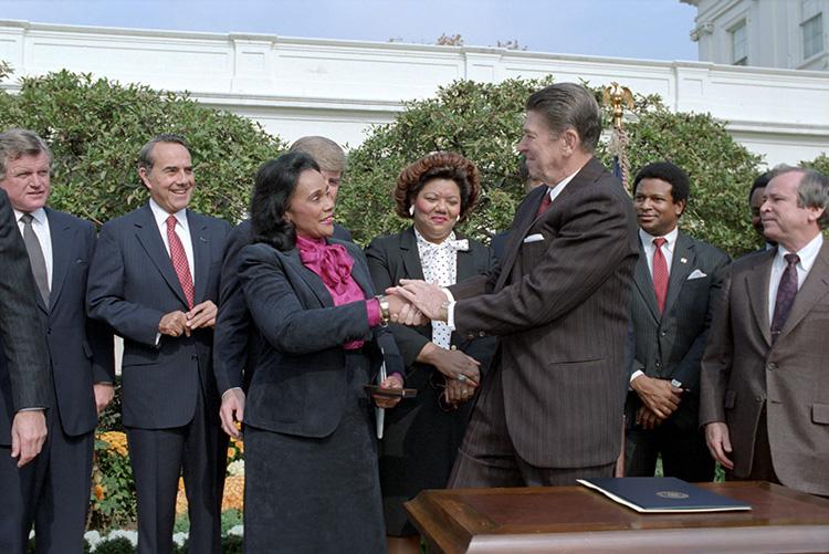 President Ronald Reagan shaking hands with Coretta Scott King at a signing ceremony making the birthday of Martin Luther King, Jr. a national holiday in the Rose Garden 11/02/1983  NAID: 276563739