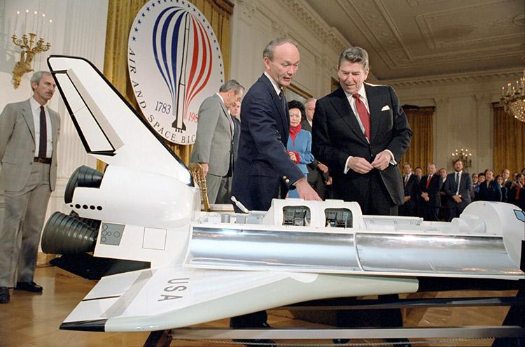 President Ronald Reagan in the East Room looking at a model of the space shuttle during a White House Ceremony commemorating the bicentennial year of air and space flight, which started 200 years ago with man’s first flight in a hot air balloon from the Château de la Muette in France 02/07/1983  NAID: 75852655