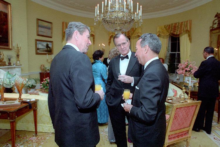 President Ronald Reagan and Vice President George Bush talking with President Jorge Blanco of the Dominican Republic in the Yellow Oval Room during the state dinner 04/10/1984  NAID: 276563827