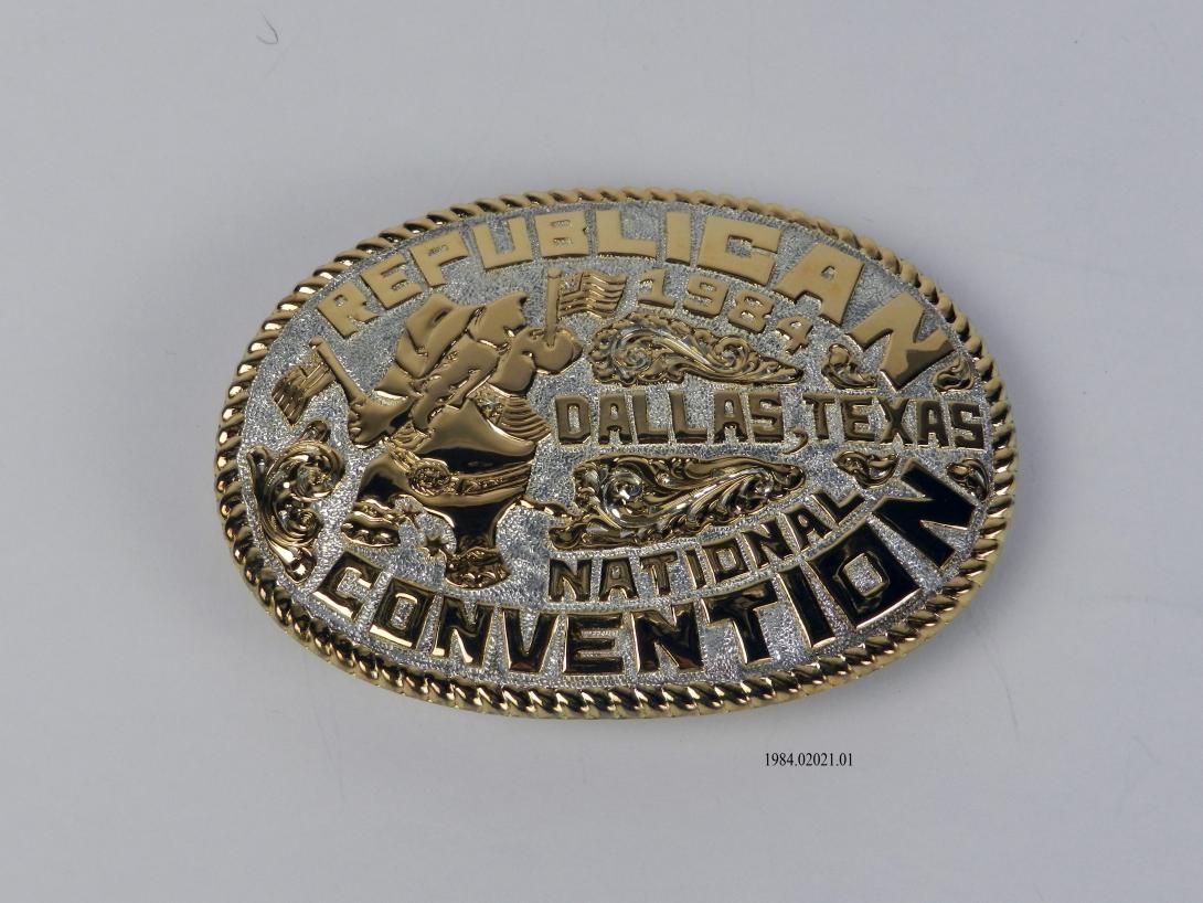Sterling silver oval belt buckle with the text "REPUBLICAN NATIONAL CONVENTION, DALLAS, TEXAS 1984." The buckle's image shows an elephant standing on its back legs dressed like a cowboy and waving two American flags. The back of the buckle is stamped "CRUMRINE MFG RENO NV USA 22 K GOLD ON STERLING."