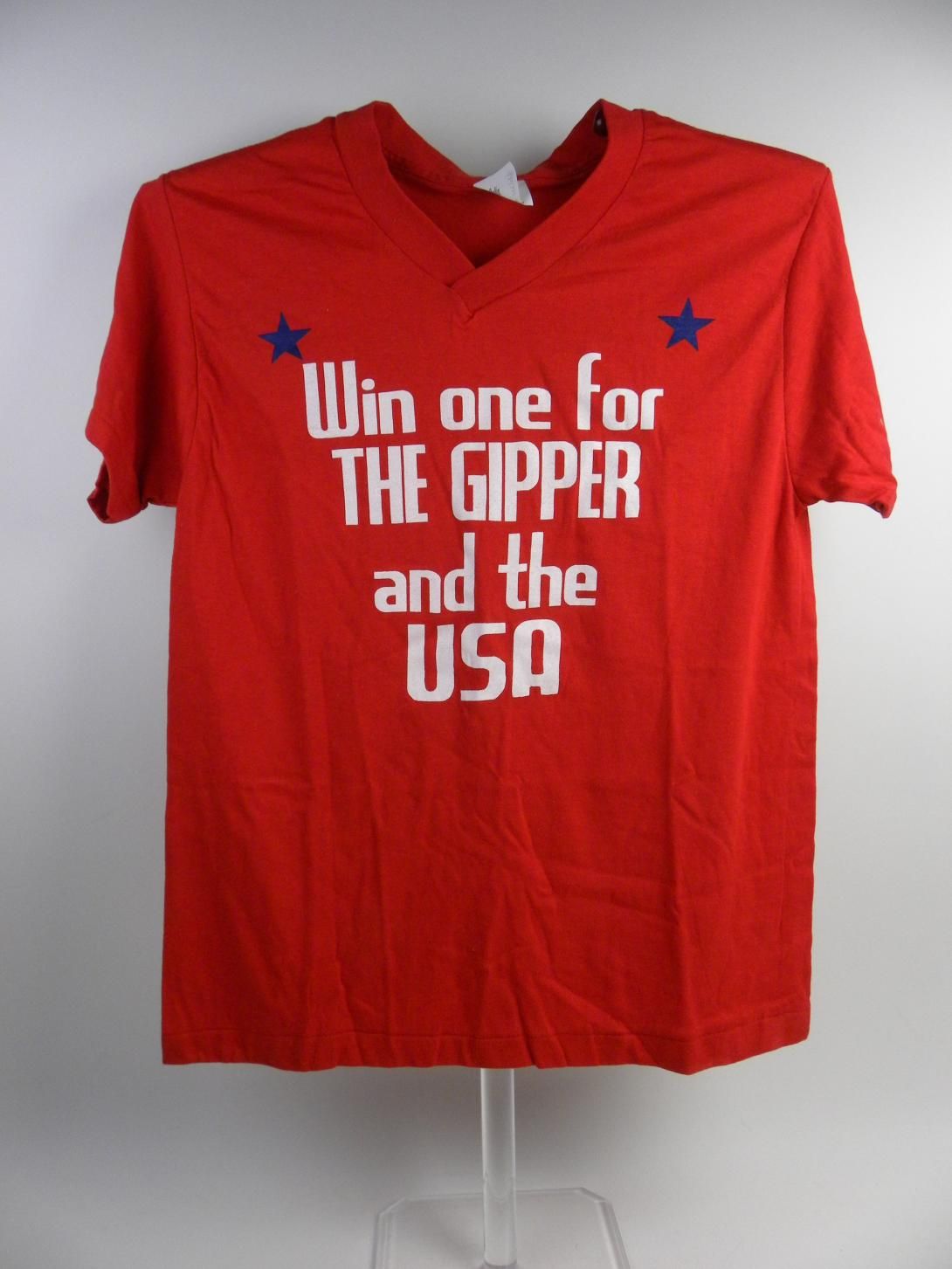 A red t-shirt with white text stating "Win one for THE GIPPER and the USA" and blue stars near the shoulders