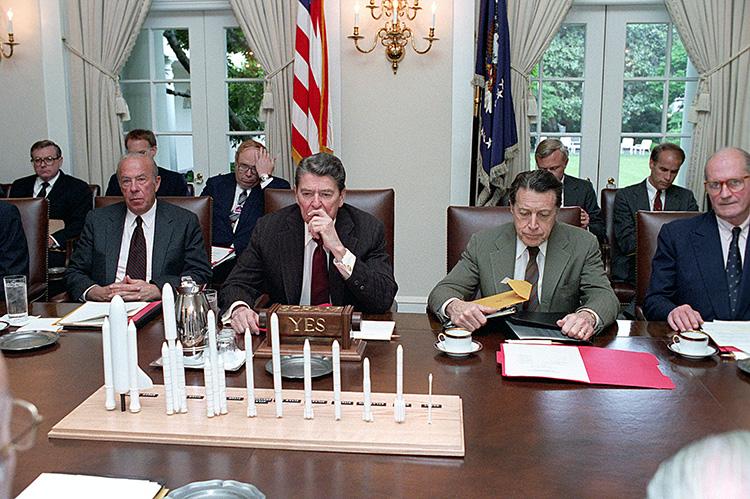 President Ronald Reagan viewing a model of NASA rockets during a National Security council (NSC) meeting in the Cabinet Room 05/15/1986  NAID: 276564353