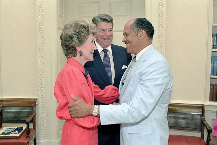 President Ronald Reagan and Nancy Reagan with Eugene Allen, retiring maître d’, in the Oval Office during a farewell photo opportunity 07/17/1986 NAID: 75854971