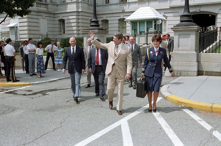 President Reagan walking from the Old Executive Office Building (OEOB) to the White House with military aide Vivien Crea, Dr. Hutton, and Marlin Fitzwater 08/03/1987  NAID: 276564533