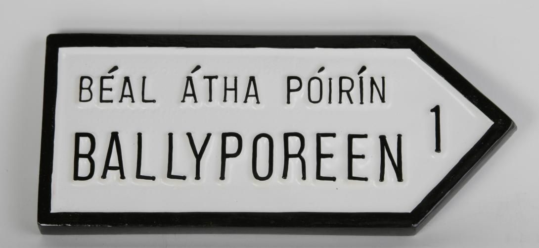 Sign, handmade shaped like an arrow white with black border, written in Gaelic in black. Tag on back “Handmade in Ireland by Polycrafts Shannon” Donor Credit Line: John T. Hay Collection. On display at The Ronald Reagan Presidential Library and Museum in the permanent exhibit Foundations of a Leader. Artifact ID: 1989.00001.668