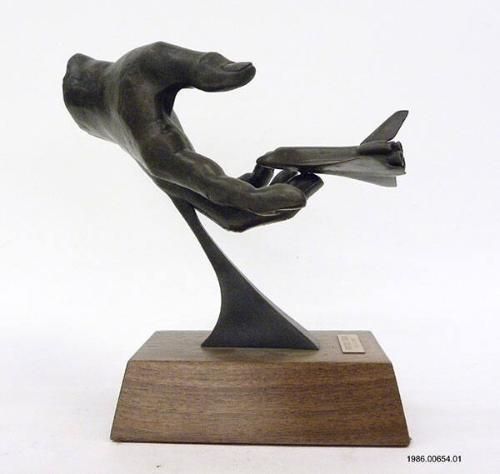 Into God’s Hand Artifact ID: 1986.00654.01 Object Type: Sculpture Gifter: Clark Coe Date: 1986 Description: A bronze sculpture of a hand reaching out to the Space Shuttle Challenger. The artwork is titled “Into God’s Hand” by Lloyd Unnasch and mounted onto a wood stand. The sculpture is numbered 8 out of 1,500.