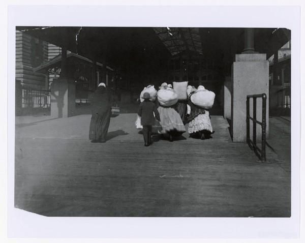 Photograph of Immigrants Walking with Luggage on Ellis Island Public Health Service Historical Photograph File 1880-1943 Record Group 90 Records of the Public Health Service 1794-1990. NAID: 595659