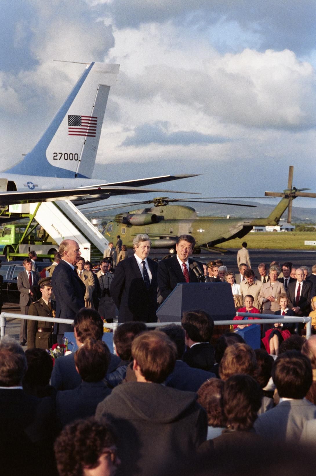 President Ronald Reagan speaking at the podium during the arrival ceremony with President Patrick Hillery and Prime Minister Garret FitzGerald at Shannon Airport in Ireland, 06/01/1984