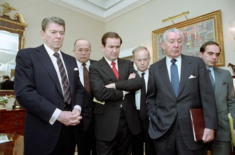 President Ronald Reagan in the Oval Office Study watching television replay of Space Shuttle Challenger explosion with John Poindexter, Pat Buchanan, Al Kingon, Don Regan, and Edward Djerejian. 01/28/1986 C33094-13. NAID: 75854573.