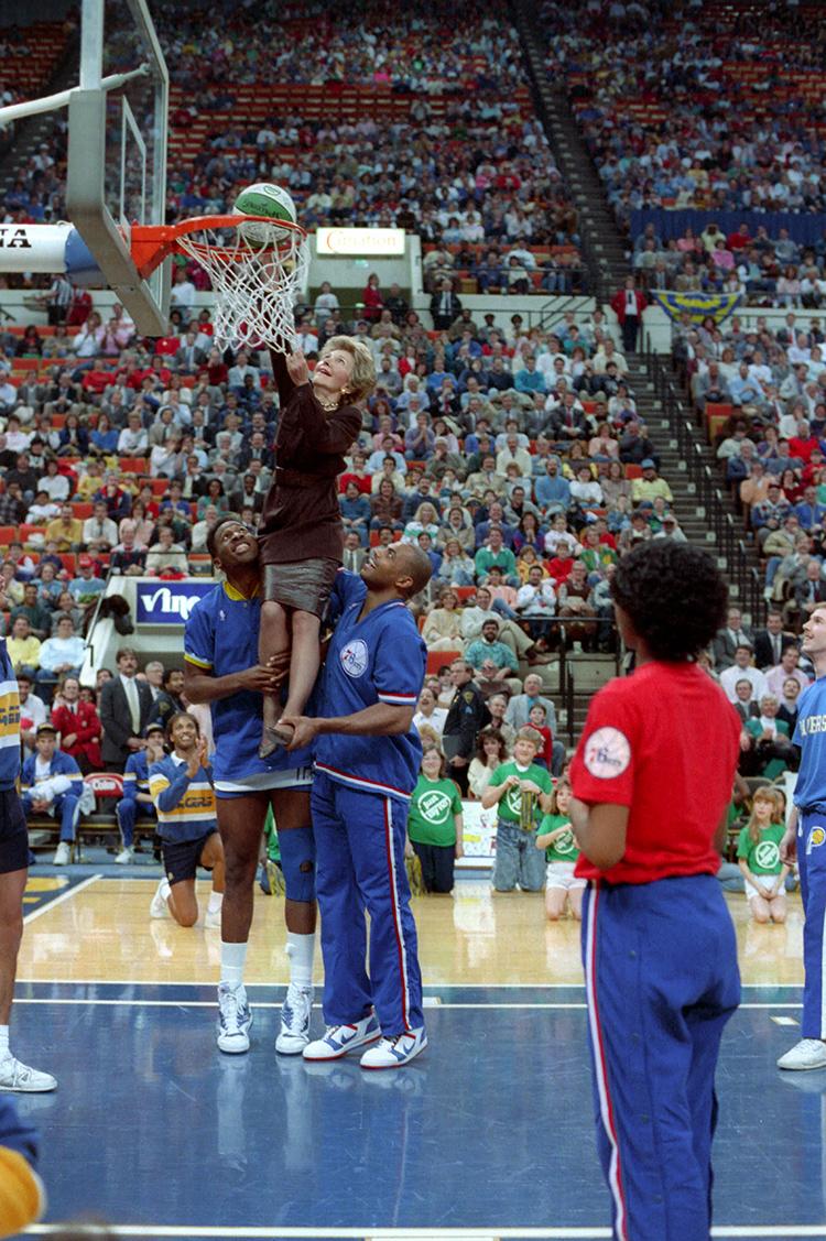 Nancy Reagan being lifted to the basket by Charles Barkley and Wayman Tisdale at a “Just Say No” basketball game in Indianapolis, Indiana dated 02/04/1988