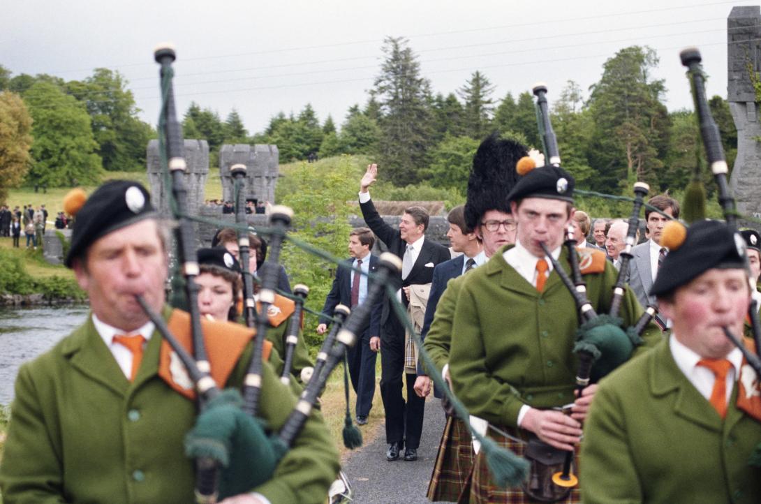 President Ronald Reagan waving and walking with bagpipers prior to departure via Marine One from Ballyporeen, Ireland for Dublin, Ireland, 06/03/1984