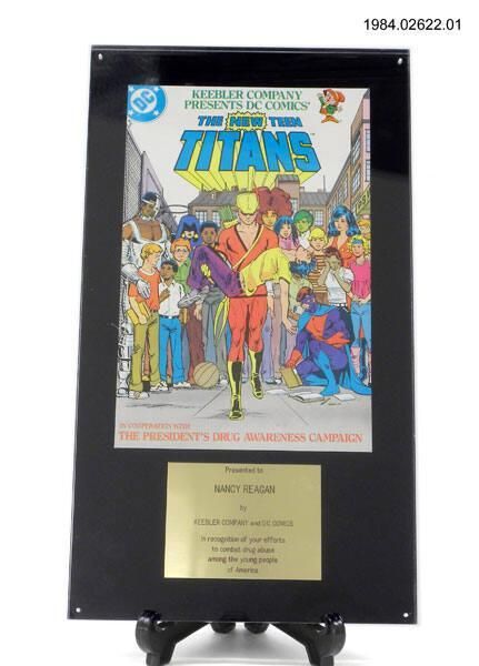 A copy of The New Teen Titans comic book on a plaque with a brass plate stating, "Presented to Nancy Reagan by Keebler Company and DC Comics in recognition of your efforts to combat drug abuse among the young people of America." 